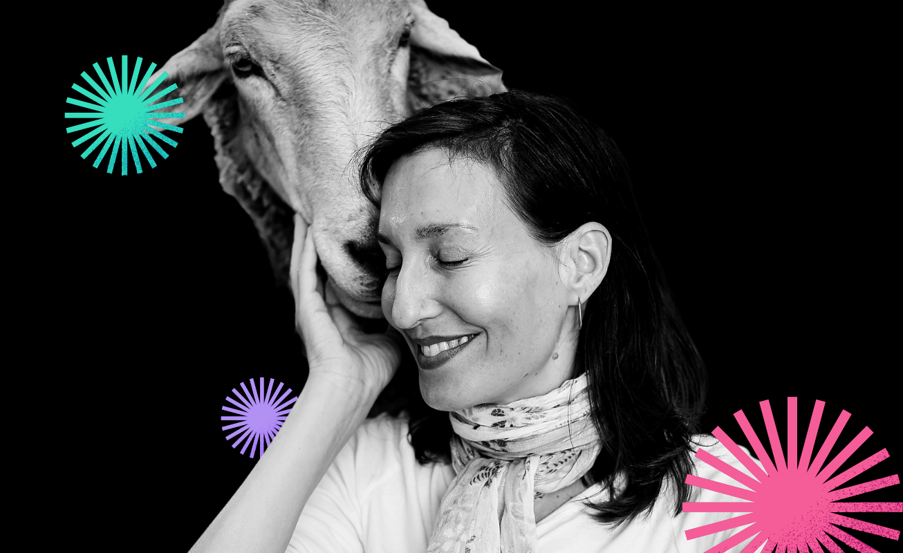 Melanie Joy smiling with sheep beside her